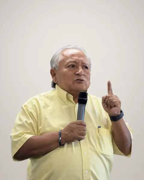 José M. Gómez habla al micrófono y levanta un dedo durante la presentación del libro